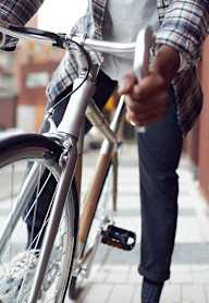 A person is holding a bicycle with one hand and giving a thumbs up with the other.
