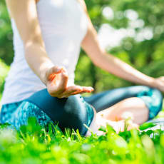 a woman sitting in the grass doing yoga