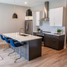 A kitchen with a white island and blue chairs.