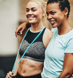 Women Smiling while Standing Next to Each Other in Gym