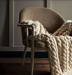 A chair with a knitted blanket draped over the back and armrests.