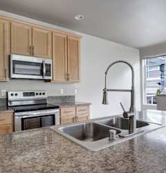 A kitchen with granite countertops and wooden cabinets.