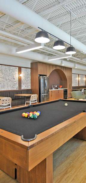 A pool table is in the middle of a room with a couch and chairs.