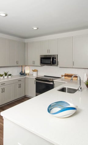 a white kitchen with stainless steel appliances and a white counter top