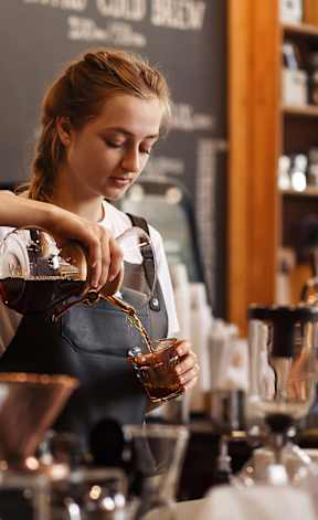 A barista is making a drink at the counter.