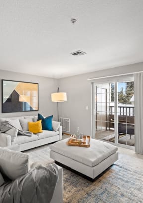 a living room with a couch and a chair and a door to a balcony