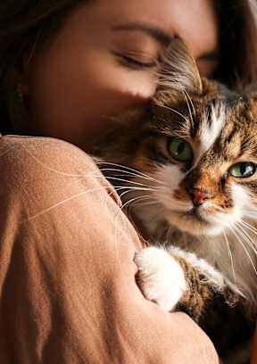 A woman is hugging a cat with green eyes.