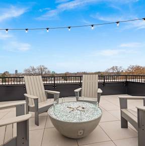 A patio with a hot tub and chairs.