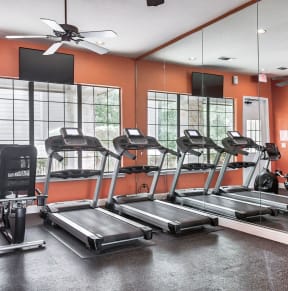 a fitness center with cardio equipment and large windows