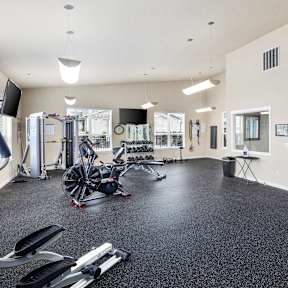 A gym with a variety of equipment including treadmills, weights, and exercise machines.