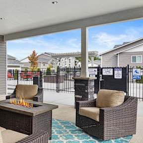 A patio with a couch, chairs, and a fire pit.