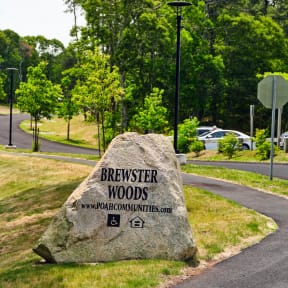 a large rock with the words brewery woods written on it in front of a road and trees