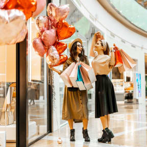 Women at Shopping Mall Holding Shopping Bags and Balloons