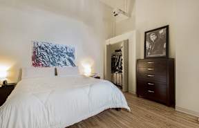 a bedroom with white bedding and a large painting on the wall