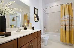 A bathroom with a white sink and a yellow shower curtain.