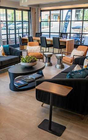 A living room with a black couch and a brown chair at Sterling Nashville West Apartments, Nashville, Tennessee