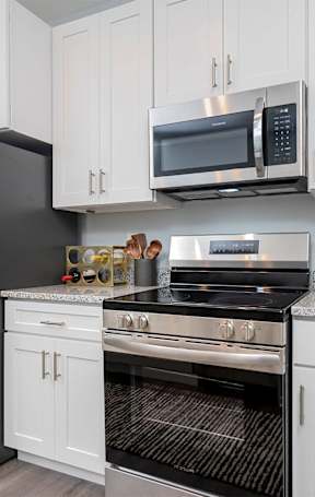 A modern kitchen with a stainless steel refrigerator, microwave, oven, and cabinets.