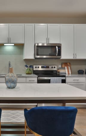 a kitchen with white cabinets and a table with blue chairs