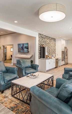 A living room with blue chairs and a stone wall.