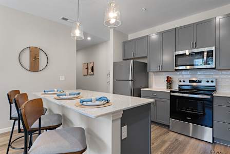 A kitchen with a white countertop and grey cabinets.