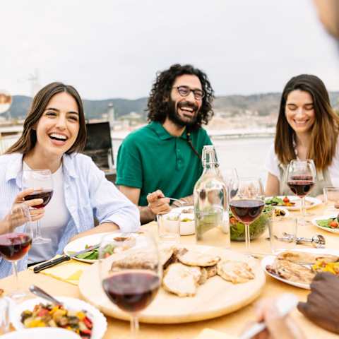 Friends Smiling while Having Food and Drinks