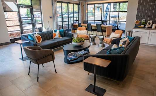 A living room with a black couch and a brown chair at Sterling Nashville West Apartments, Nashville, Tennessee