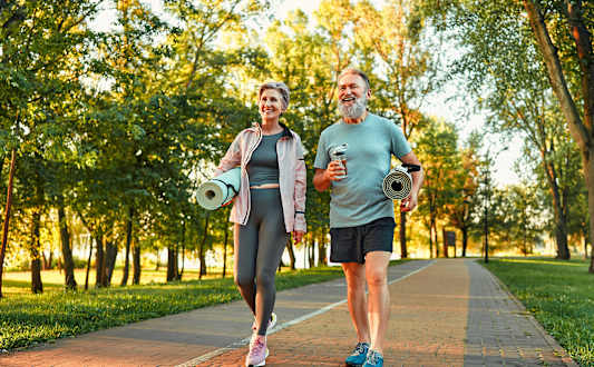 Two people walking on a path in a park.