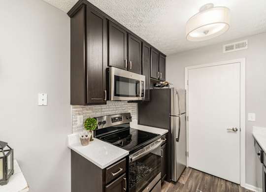 A kitchen with dark brown cabinets and a black stove top oven.
