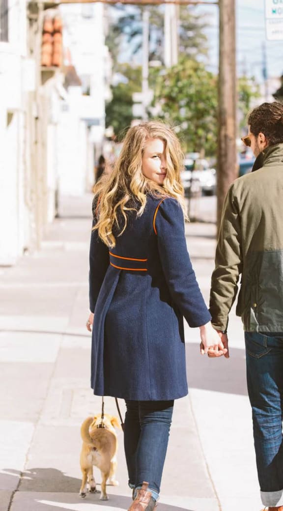 a man and woman walking a dog down a sidewalk