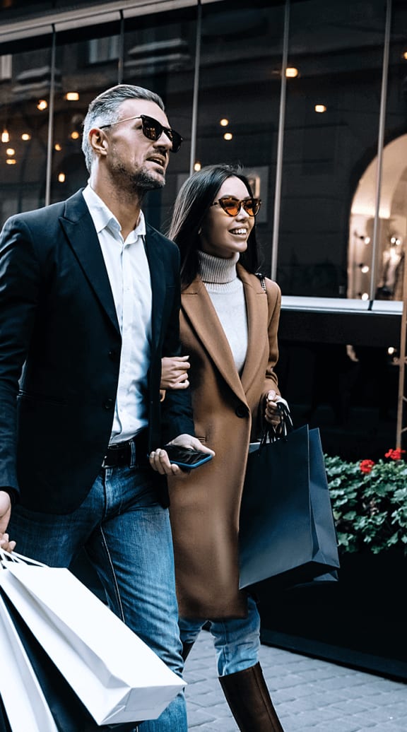 a man and woman walking down the street with shopping bags