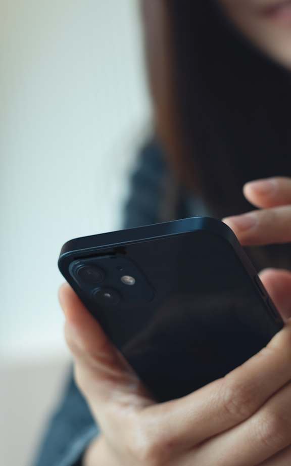 A person holding a black smartphone in their hands.