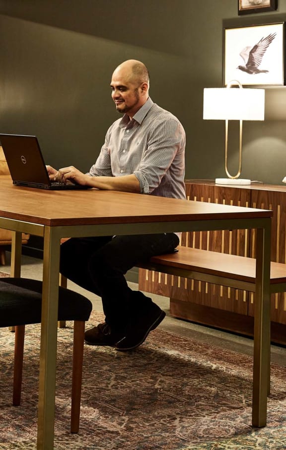 a man sitting at a table working on a laptop  at 888 Hilgard – Furnished Apartments, Los Angeles, CA