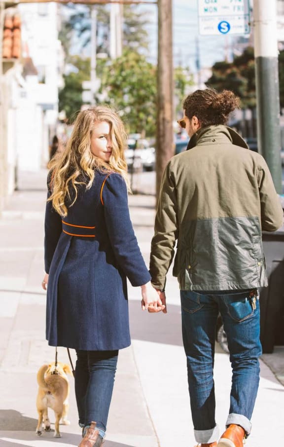 a man and woman walking a dog down a sidewalk