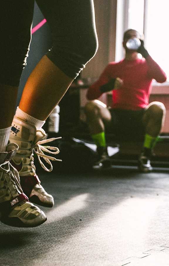 A person is jumping in a gym with others sitting and working out.