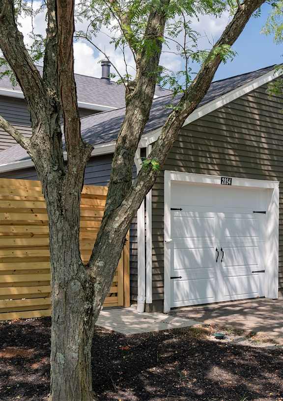 A house with a white garage door is surrounded by a wooden fence.