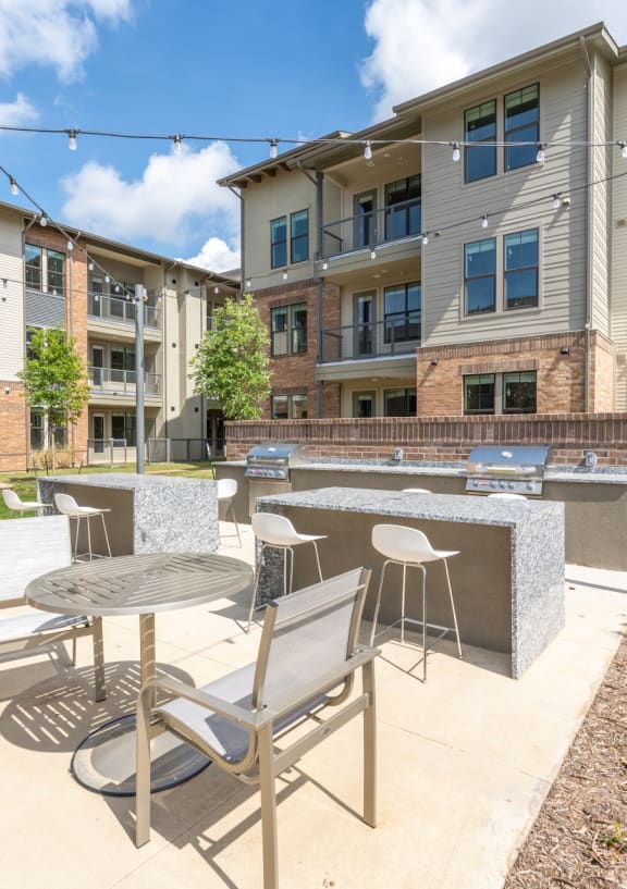 a patio with a table and chairs in front of an apartment building