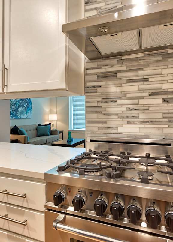 A modern kitchen with a stainless steel gas stove and white cabinets.
