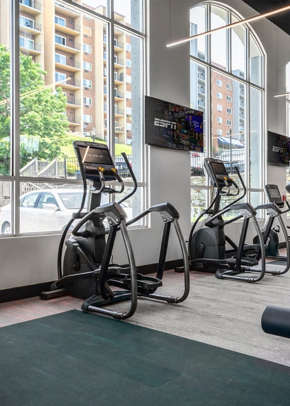 a gym with weights and cardio equipment in a building with large windows at The Heights Apartments, Cincinnati, 45220
