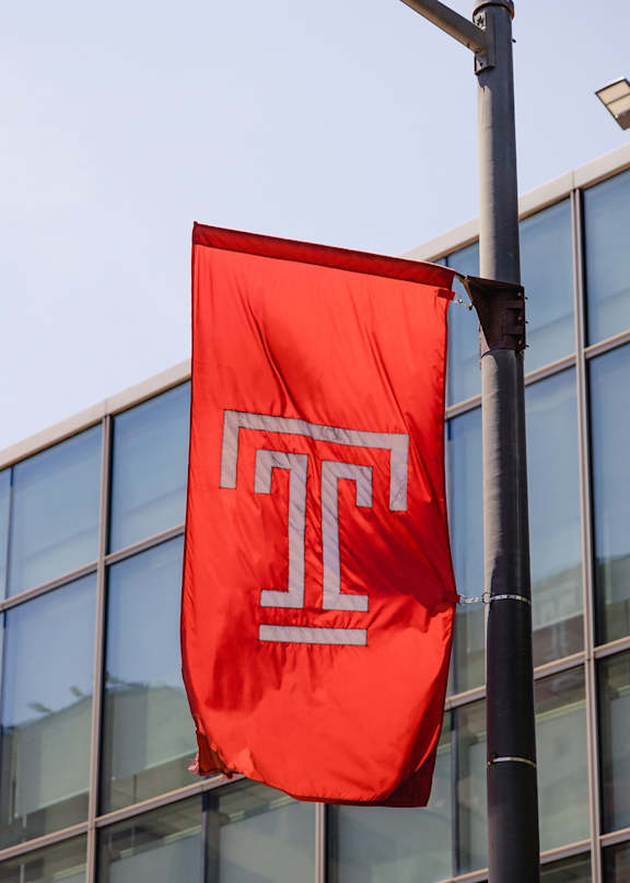 A red flag with a white letter T on it is hanging from a pole.