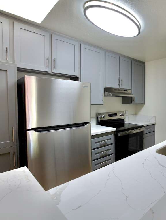 the spacious living room and kitchen with white walls and a ceiling fan at Brookhollow Apartments, West Covina , California