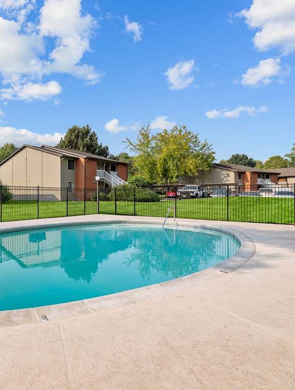 A swimming pool in a residential area with houses and trees in the background.