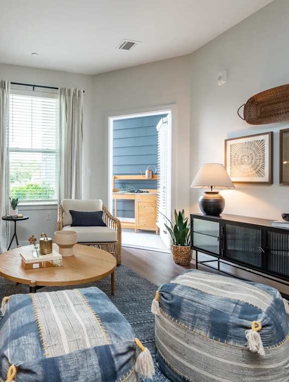 A living room with a white couch, a coffee table, and a blue and white striped ottoman.