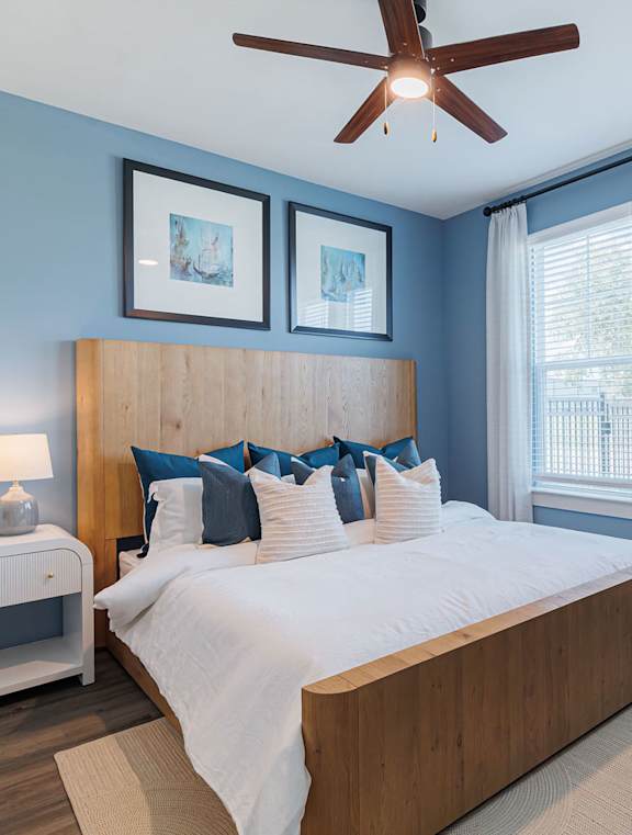 A bedroom with a bed, a ceiling fan, and a window with blinds.