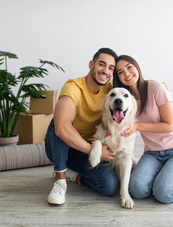 Young Couple Sitting on Floor in New Home with Dog
