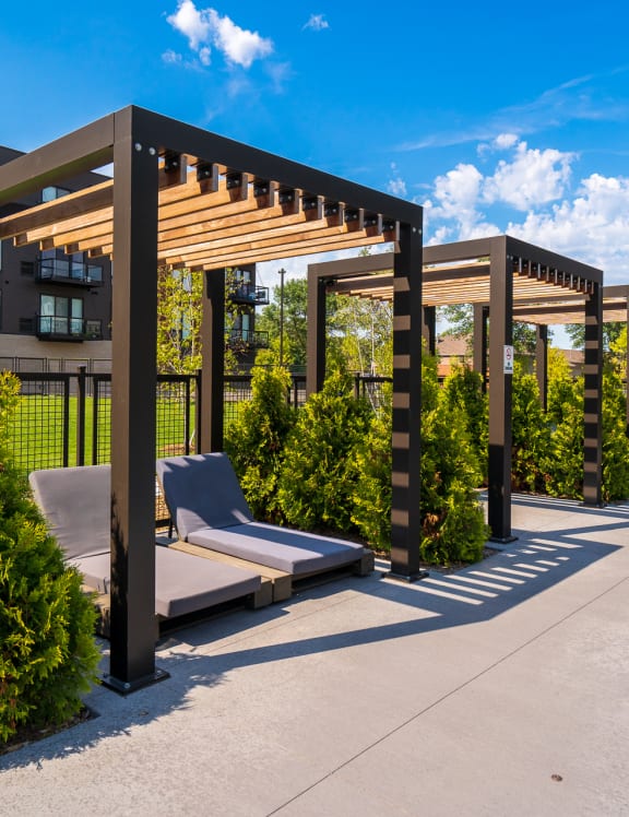 a pergola with lounge chairs on a patio next to a pool