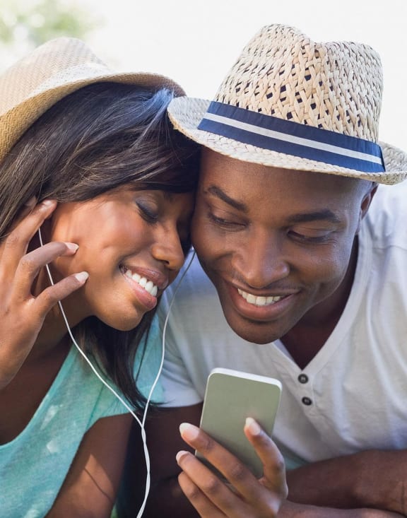 a man and woman laying on the grass looking at a cell phone
