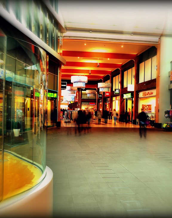 A blurry image of a shopping mall with a person walking in the distance.