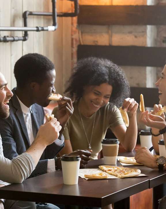 Group of Friends Laughing while Having Food and Drinks Together