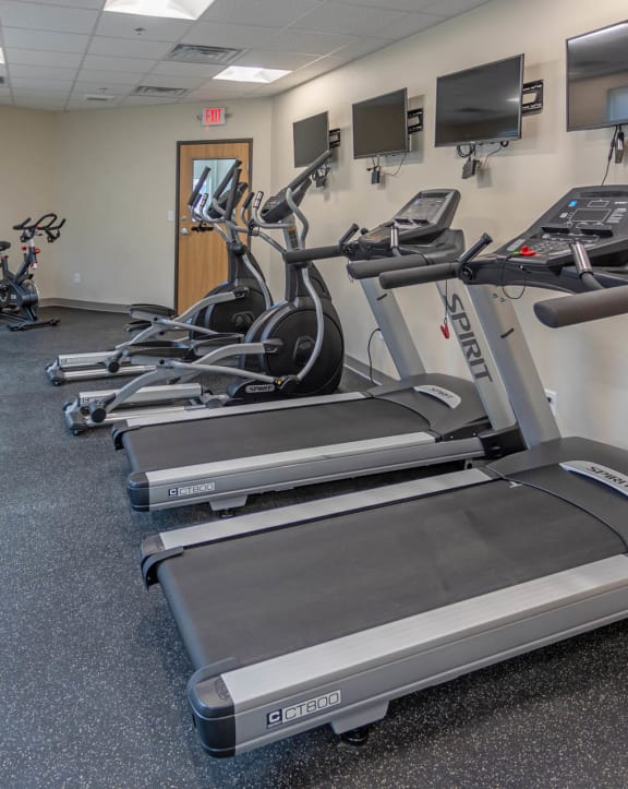 a room filled with cardio equipment and flat screen televisions