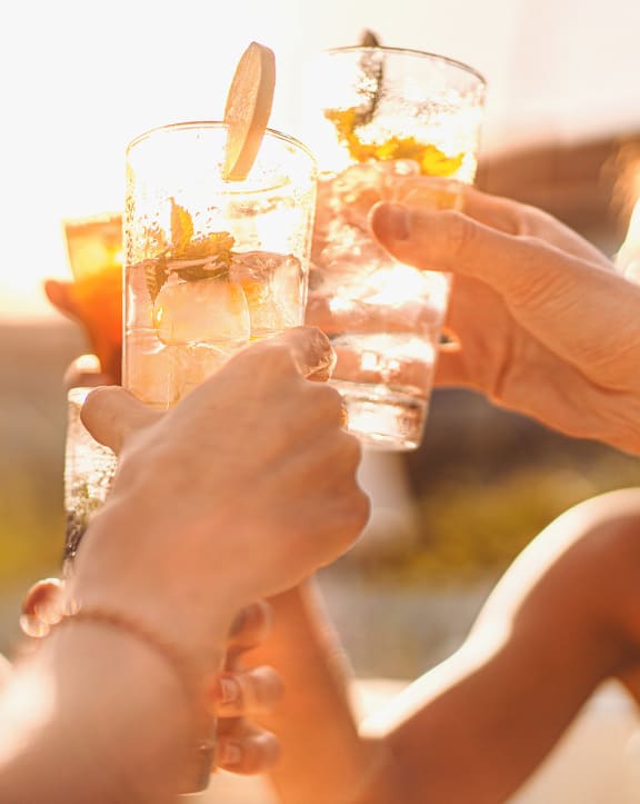 people holding up glasses of cocktails at a party